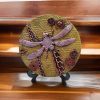 Intricate steampunk dragonfly art piece with mechanical gears on a rustic wood slice