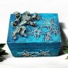 A vibrant blue wooden box with gold decoration on the lid that include stars and a central figure of a lion.