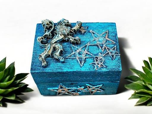 A vibrant blue wooden box with gold decoration on the lid that include stars and a central figure of a lion.