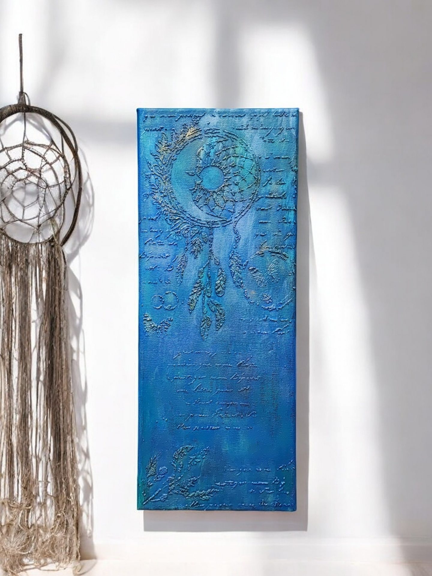 A vertical canvas featuring a raised dream catcher design created with texture paste on a stencil, painted in a vibrant blue with a gold and purple touch, that adds depth and interest