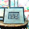 A handcrafted picture frame with a textured, rustic appearance, gold accents, and central butterfly design
