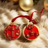 Two handcrafted Christmas tree ornaments with a red background and gold accents, featuring designs of Big Ben and British crown with holiday motifs.