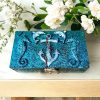 Hand-decoreted wooden keepsake box with sea life theme. Rich blue surface with resin and clay embellishments, including seahorses, an anchor and playful dolphins.