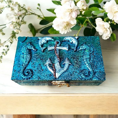 Hand-decoreted wooden keepsake box with sea life theme. Rich blue surface with resin and clay embellishments, including seahorses, an anchor and playful dolphins.