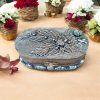 Handcrafted oval trinket box with antique-style metallic floral and leaf detailing, featuring a decorative clasp and sturdy design.